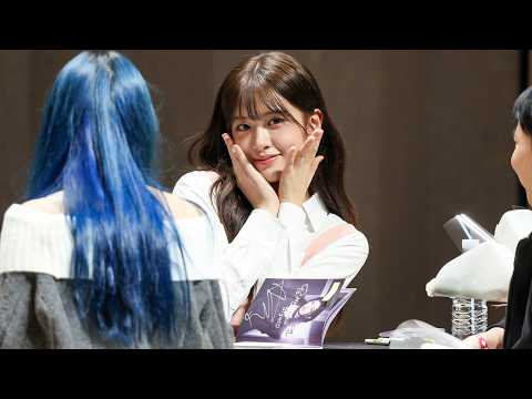 IVE's Yujin smiling brightly at a fansign event, looking directly at a fan.
