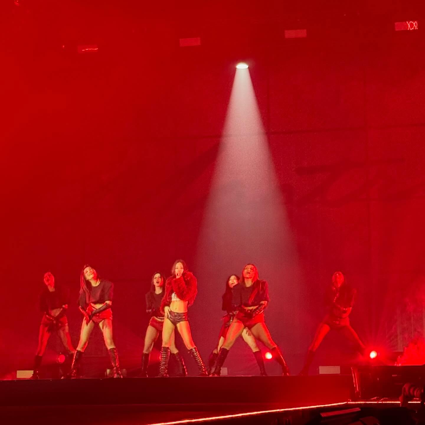 JENNIE posing at ComplexCon HK, smiling with a playful expression, holding a sign.