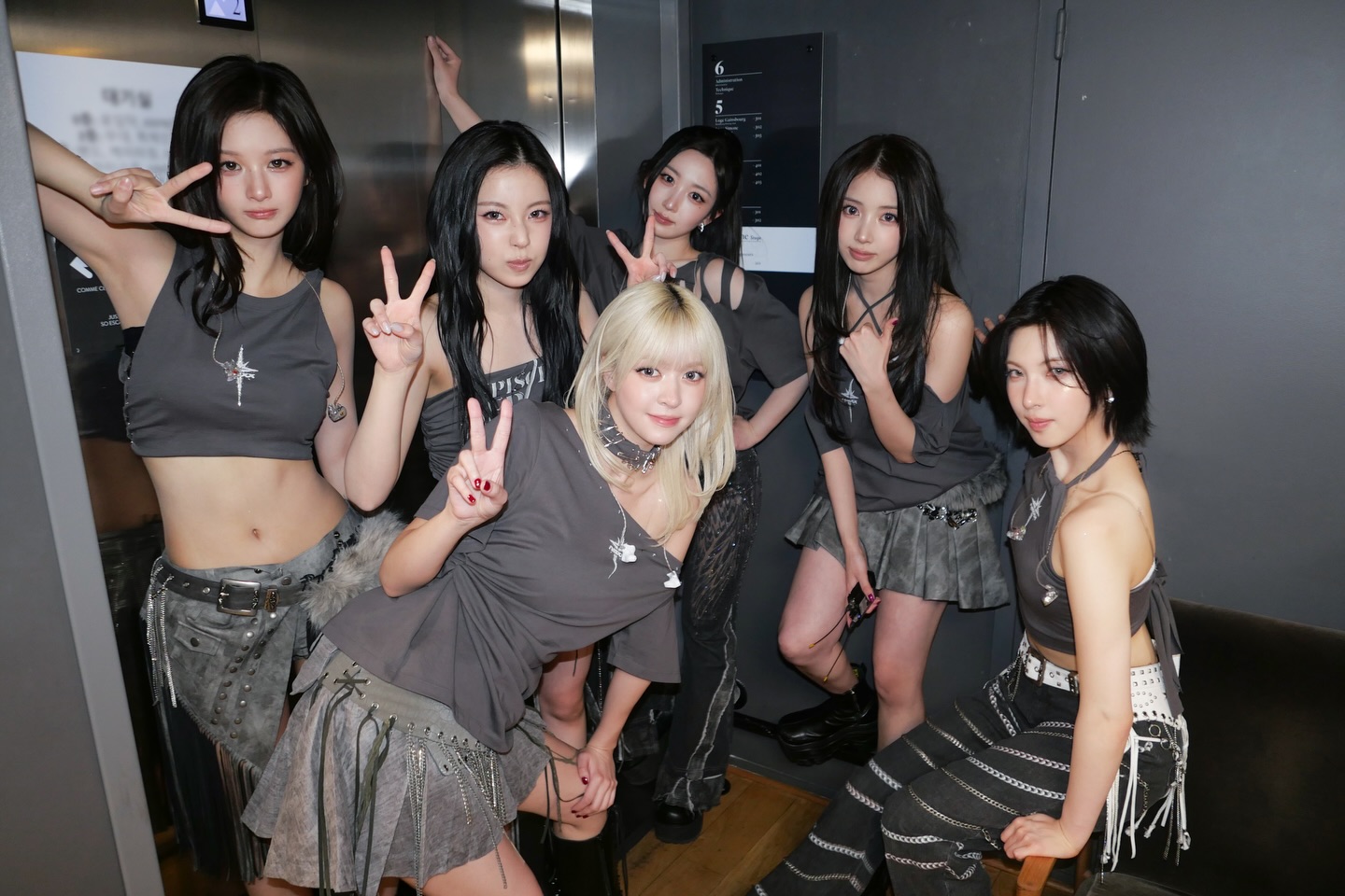 NMIXX members posing in front of a colorful backdrop in Paris