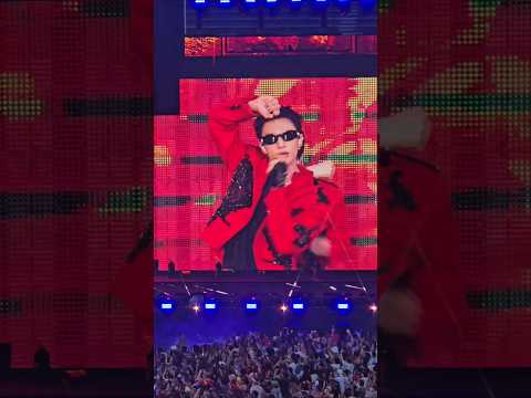 Stray Kids members performing energetically on stage at a concert with a vibrant light show.